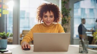 Woman using a laptop and mouse in an office